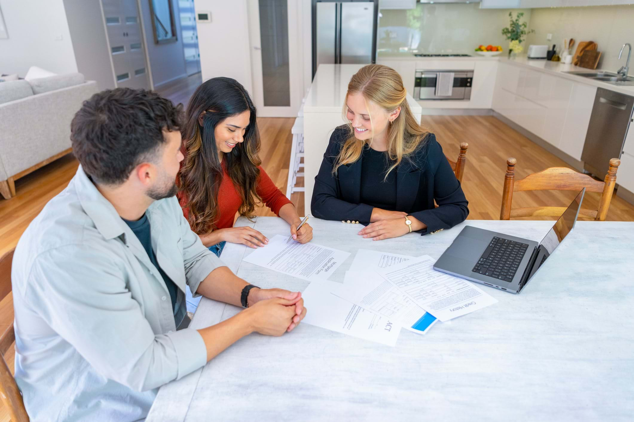 Couple sign contract with estate agent while sat at kitchen table